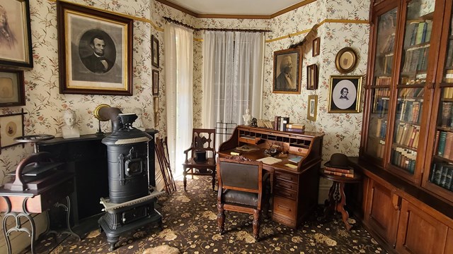 Frederick Douglass's library with desk, chair, books, and portraits on the wall.