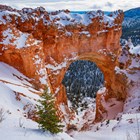 Red rocks in an arch formation covered in snow.