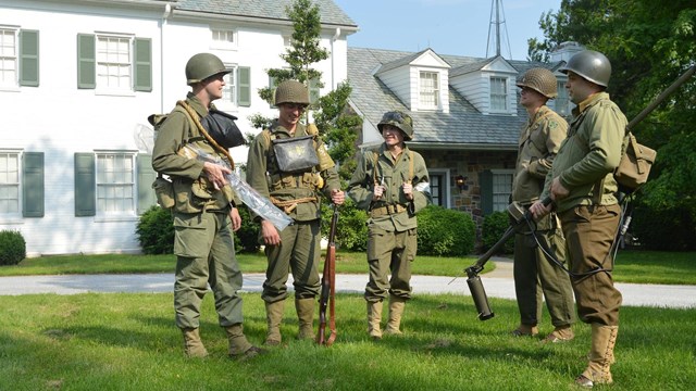 An image showing volunteers in World War II uniforms speaking to visitors
