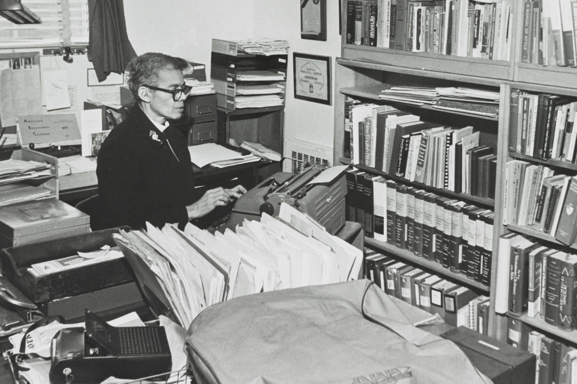 Pauli Murry working at a her desk in an office with many books.