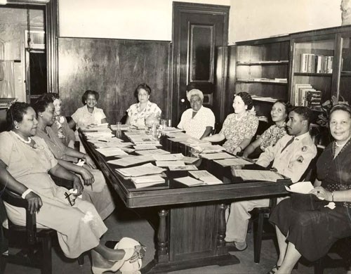 Mary McLeod Bethune with other African American women and men gathered around a large table.