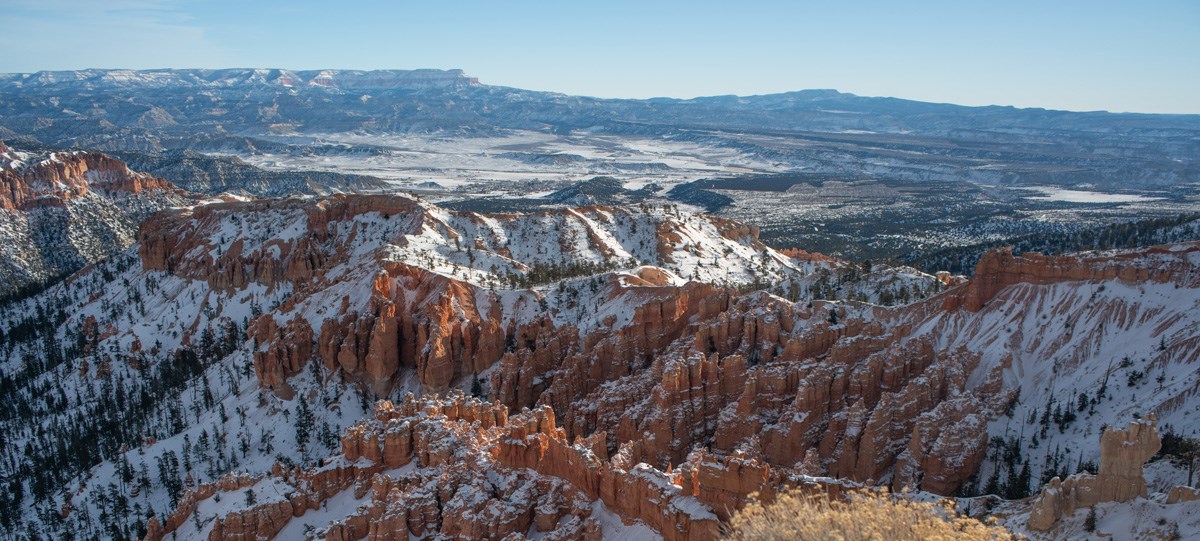 An amphitheater of red rock formations covered in snow.