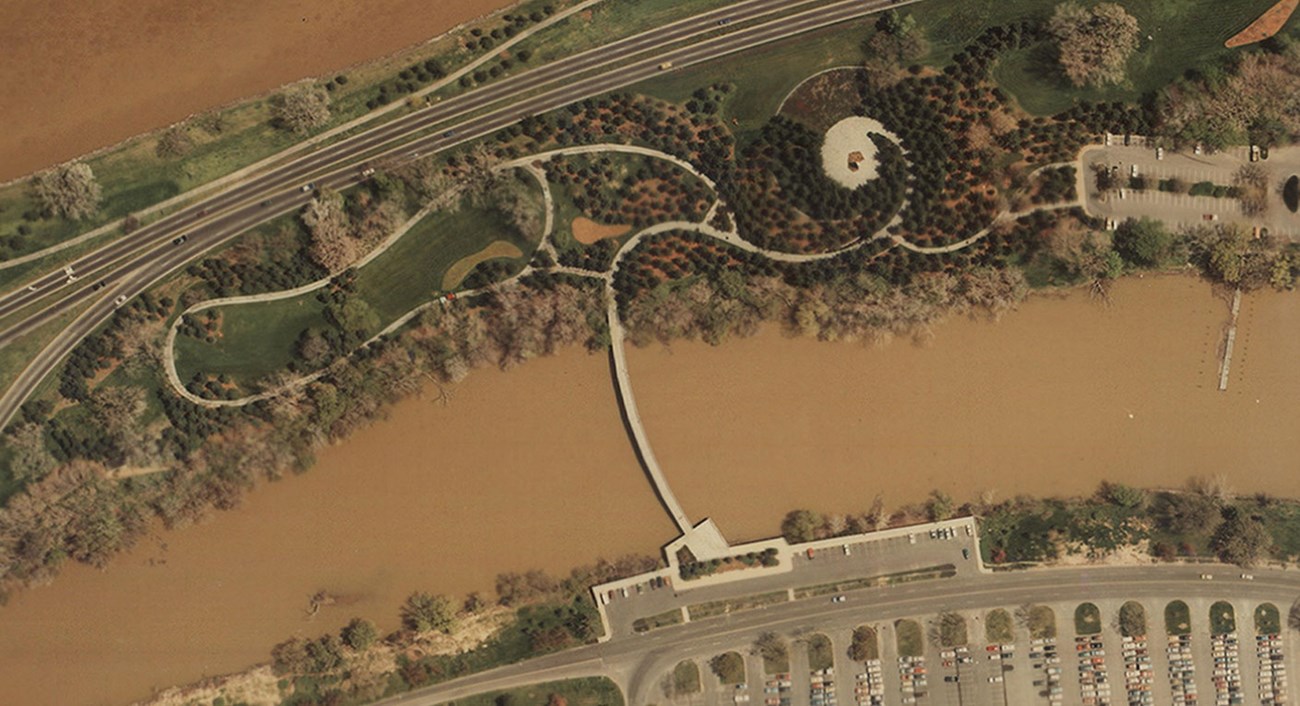 Aerial view of LBJ Memorial Grove on Columbia Island, showing tree canopies, parking, paths, highways, and waterways.