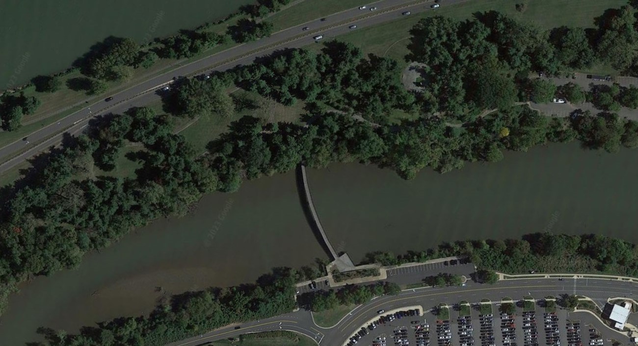 Aerial view of LBJ Memorial Grove on Columbia Island, showing tree canopies, parking, paths, highways, and waterways.