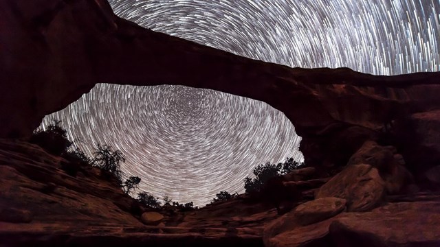 Time-lapse of night sky above an arch