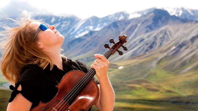 Woman with a string instrument in a mountainous area