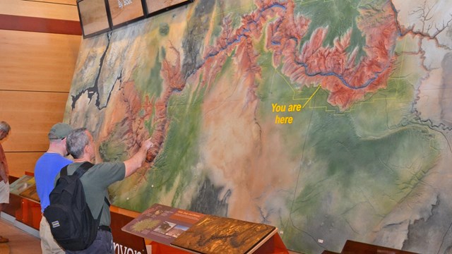 Two visitors looking up at a large map