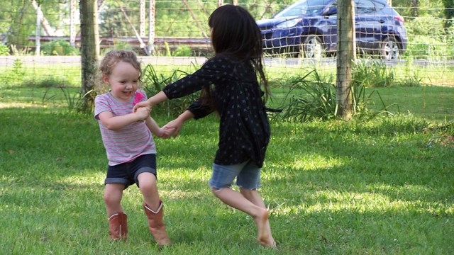 Two kids dancing in the grass