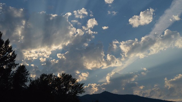 View of open field and cloudy blue sky.