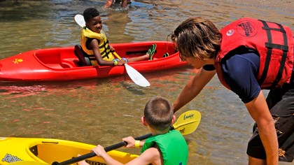 Woman helping two young children in kayaks
