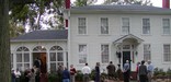 A group of people stand in front of a two-story frame house, home to Major Ridge in Rome, Georgia