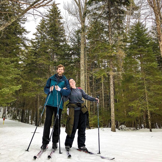 Man and woman standing in cross-country skis on a snow-covered carriage road