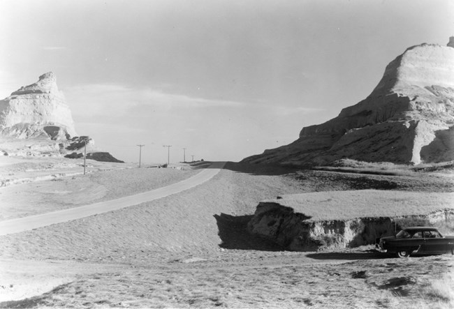 A paved road passes between sandstone bluffs.