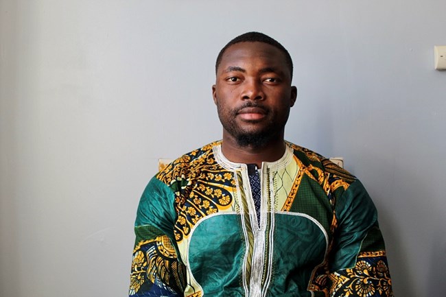 man posing without smiling for a photo with traditional african attire