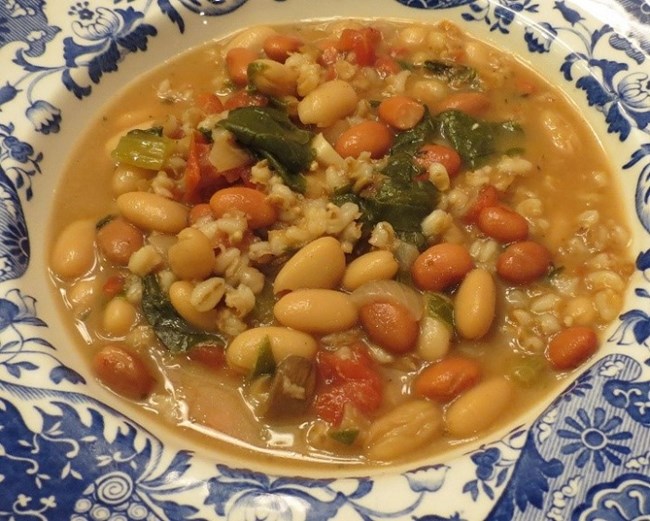 Bowl of soup with white beans, carrots and kale.