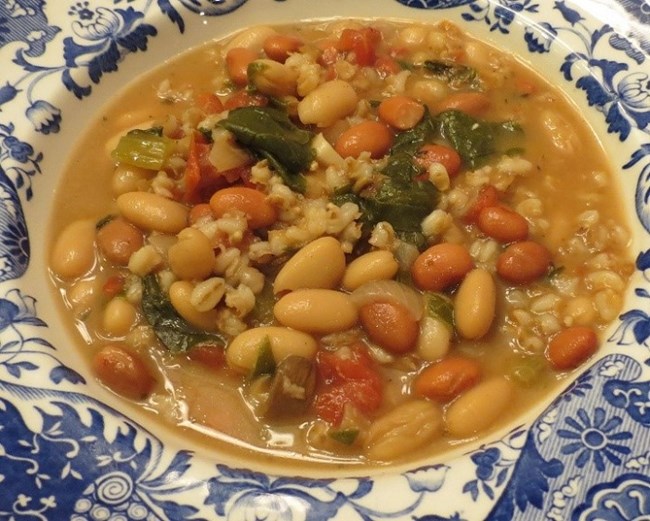 taste of fova soup Bowl of soup with white beans, carrots and kale.