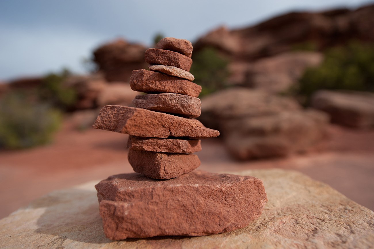 small stack of red rocks in a conical shape on top of a boulder