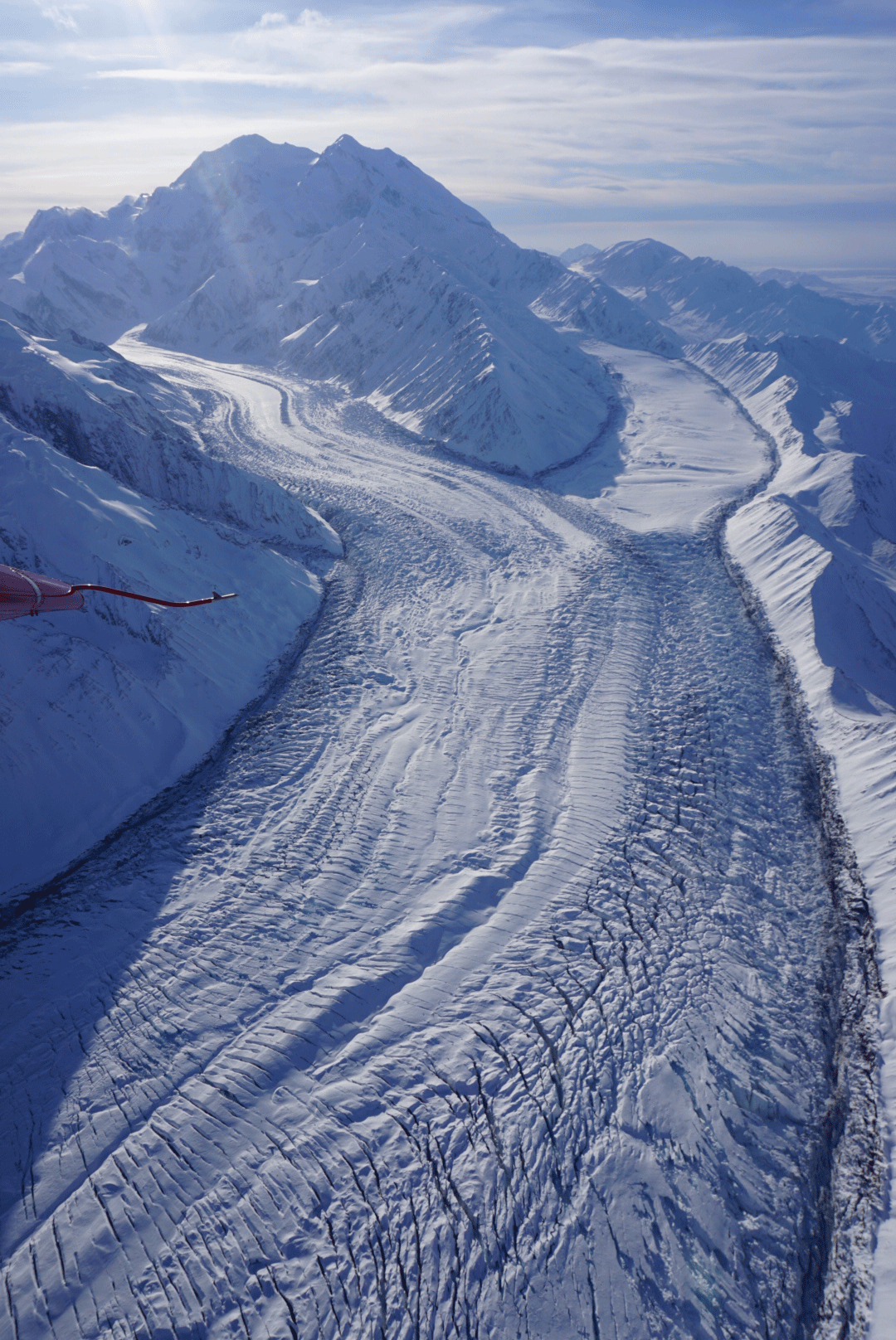 a huge glacier rising up into snowy mountains