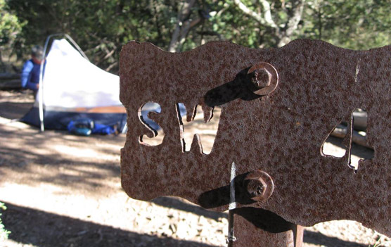 Setting up camp; campsite sign with tent in the background