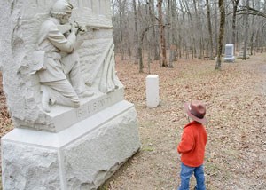 A junior ranger ranger standing in front of a stone monument