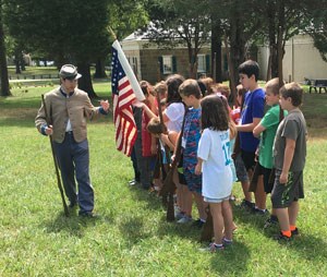 A park ranger wearing a confederate uniform leads a program for a small group of students.