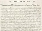 Color image of the Declaration of Independence with black handwritten text on cream paper.