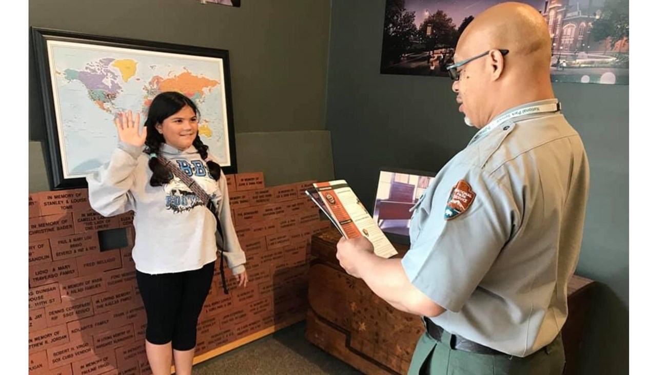 A girl is sworn in by a park ranger as a junior ranger