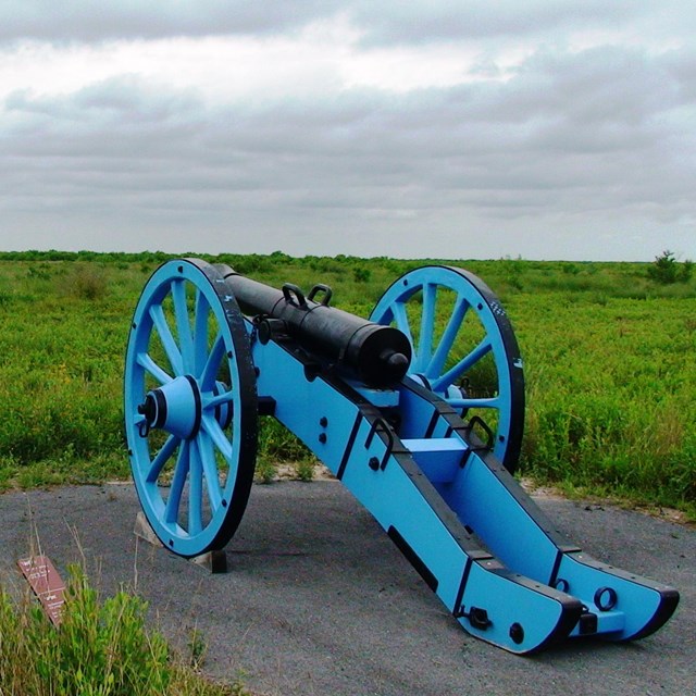 A replica of a blue, Mexican field cannon overlooks the battlefield