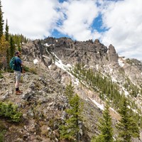 A hiker takes in the views approaching a rocky summit.