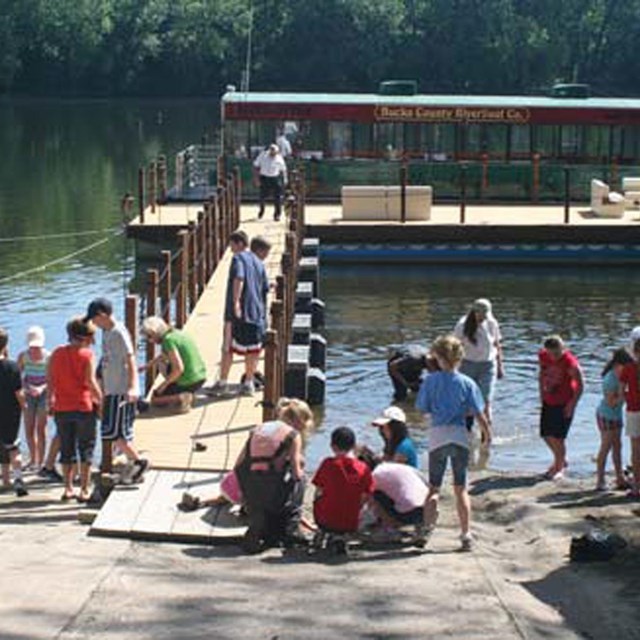 many children gathering at a dock with boat anchored to it on Lower Delaware River