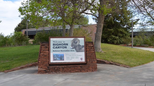The welcome sign at the Cal S. Taggart Visitor Center with trees and a sidewalk in the background