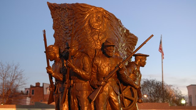 A statue of African American Civil War soldiers at sunset