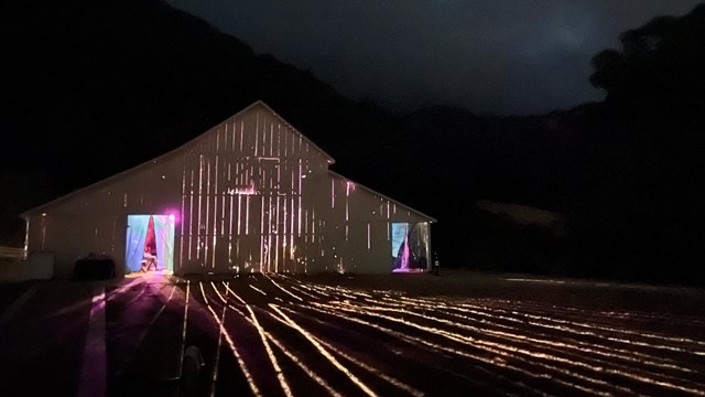 White barn with lights shining from the inside.