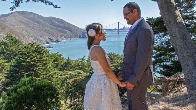 A couple in wedding attire with the Golden Gate Bridge behind