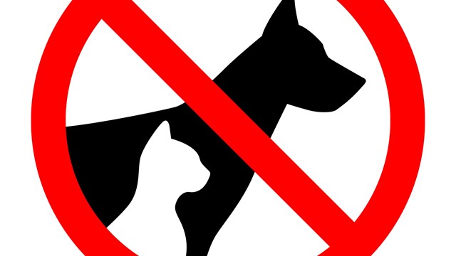 A sign with a silhouette of a dog and cat with a line mark through it.