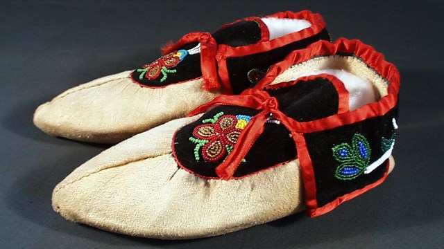 Beaded leather moccasins with satin ribbon trim.