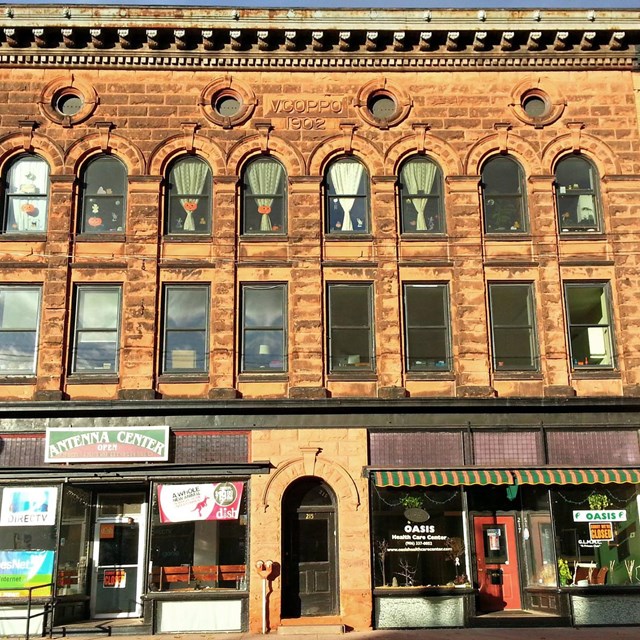 A tall three-story building with a windowed storefront on the first level.