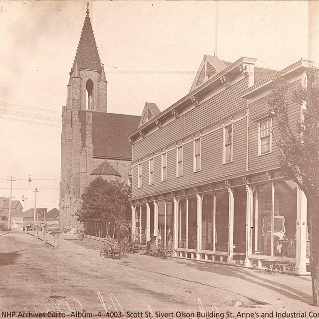 A church and storefront with a unpaved street in front.