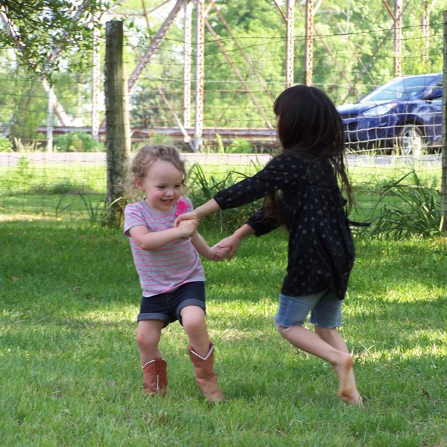 Two young kids dancing on a grass field