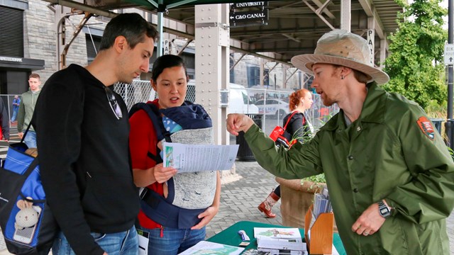 A ranger talks to visitors under a tent during an event