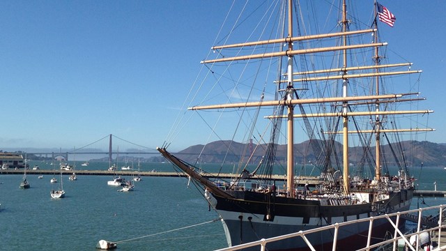 A restored historic sailing ship built in 1886 moored along a pier.