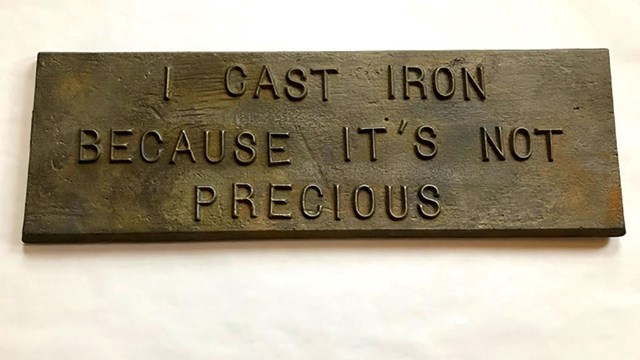 Cast iron plaque with the words "I cast iron because it's not precious" on it