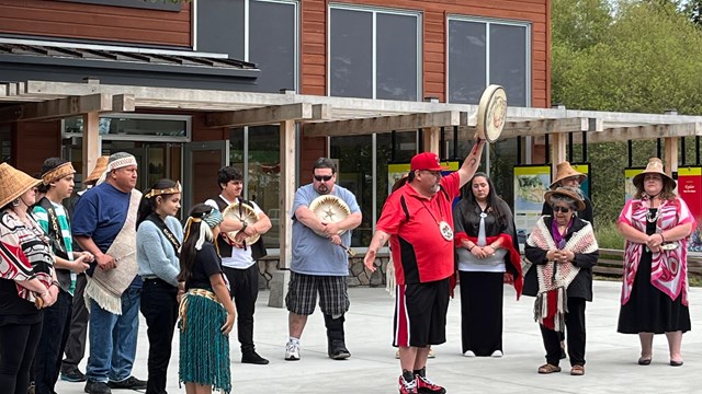 A group of people gather outside the Visitor Center building part of a Coast Salish tribal event.