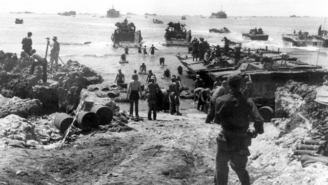 Soldiers unloading barrels of fuel from amtracs to the beach