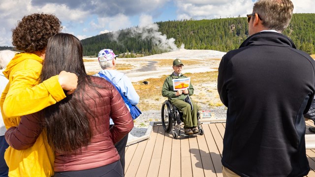 A panger gives a program on the boardwalk before an Old Faithful eruption