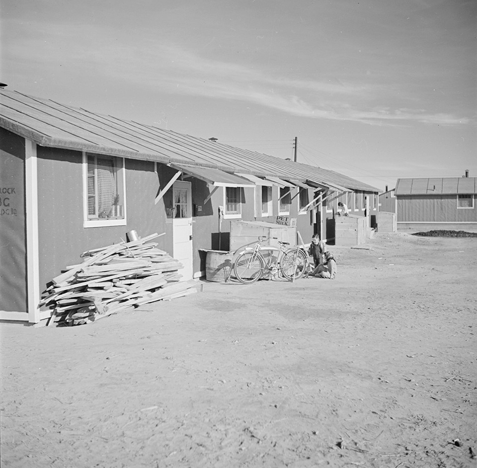 Black and white image from 1942 showing standard barracks with weathered canopies over the doors