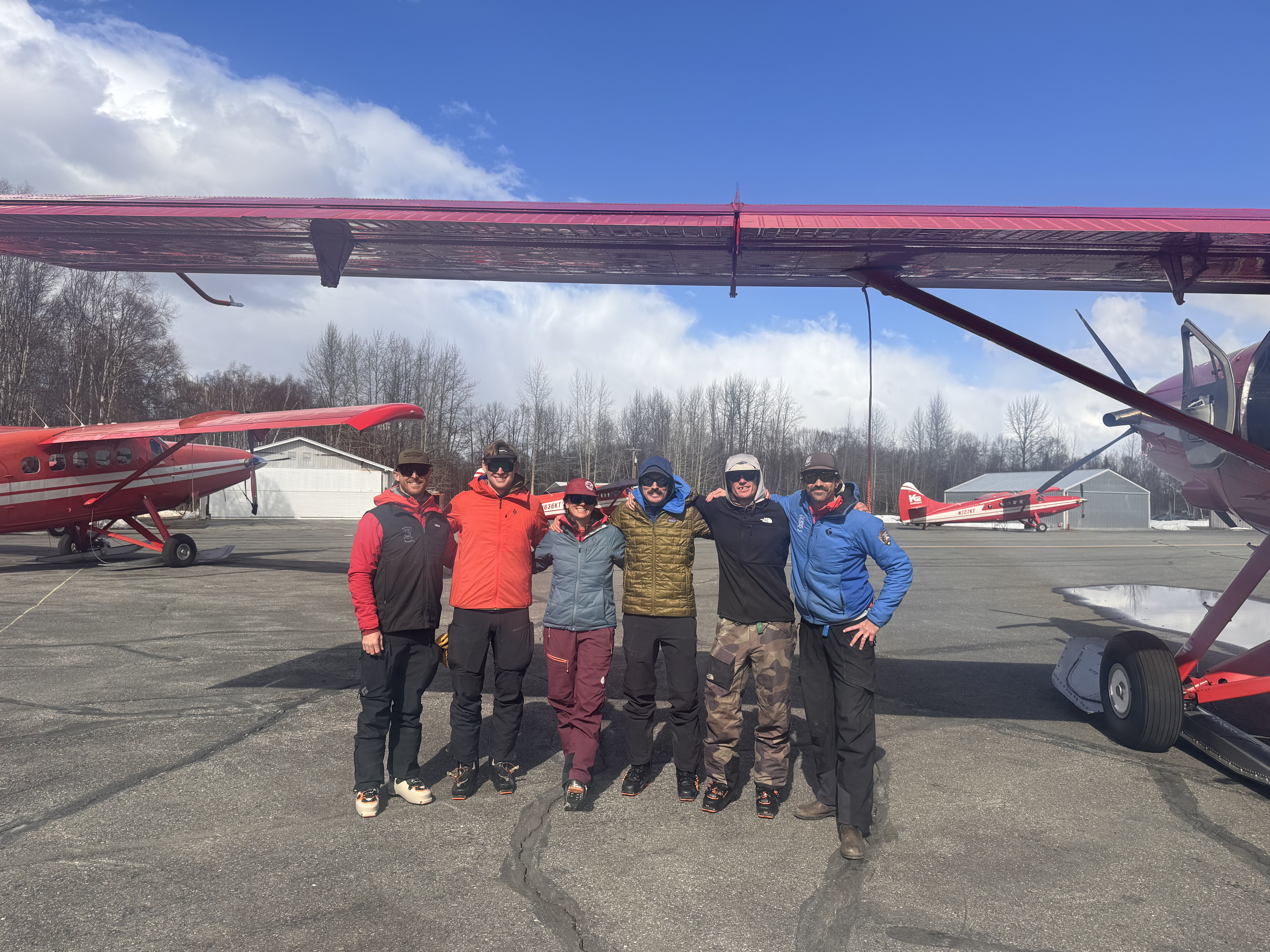 West Buttress patrol #1 A group of 6 rangers stand in a line with their arms draped over each other's shoulders under the wing of a red play