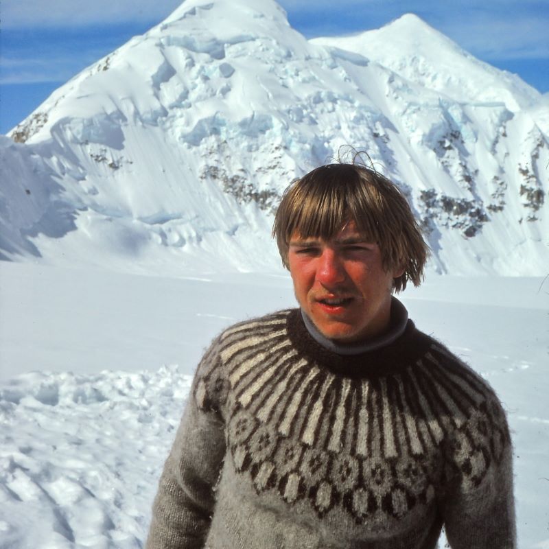 Roger Photo resized Man with sandy blonde hair wearing a brown fair isle sweater in front of a snowy mountain peak