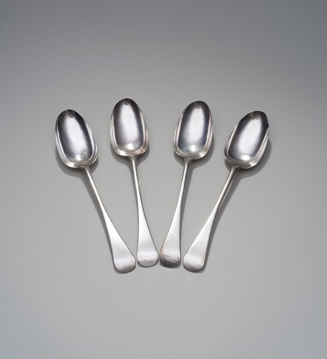A photo of four antique silver spoons on a white background.