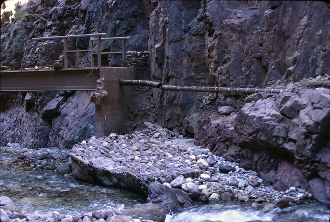 A section of a foot bridge showing damage resulting from a flood in 1966 that broke the water pipeline and washed away most of the bridge.
